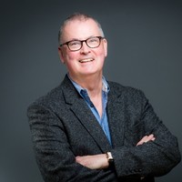 Man with glasses with folded arms in suit, smiling